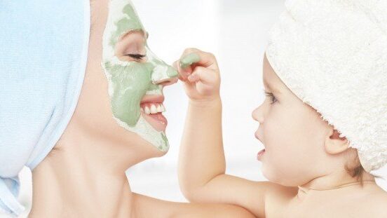 family beauty treatment in bathroom. mother and daughter baby girl make mask for face skin beauty tips